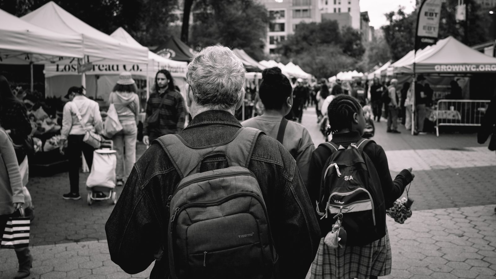 A busy outdoor pop-up market with vendor tents